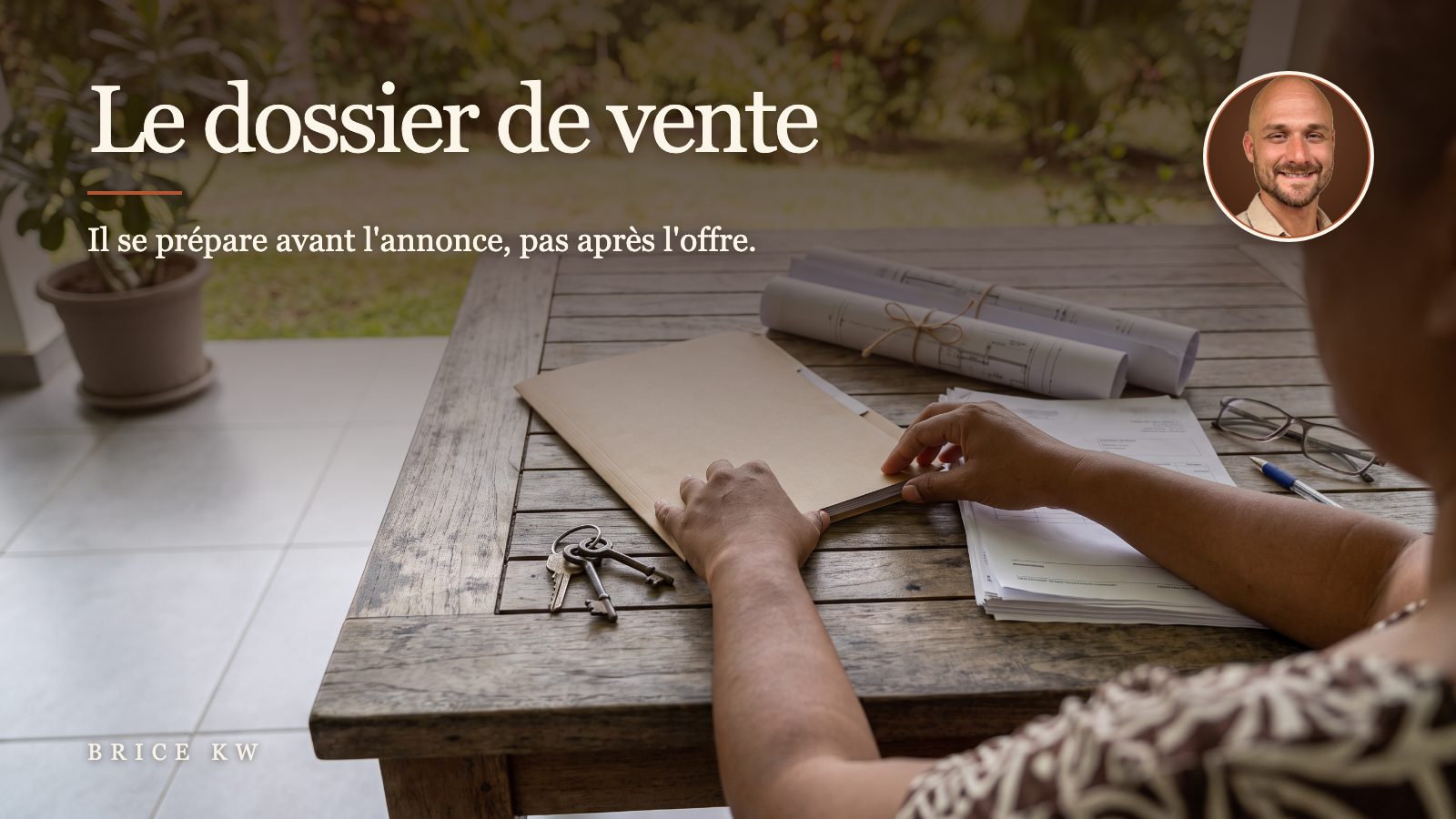 Des mains rangent un dossier de vente, plans et clés, sur une table en bois à Tahiti
